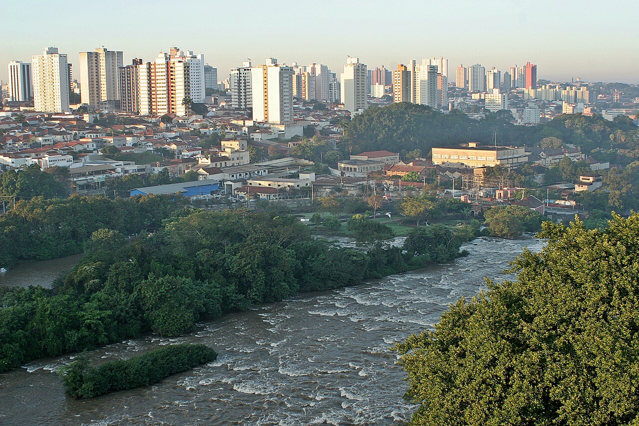 Rio Piracicaba com corredeiras e vegetação em primeiro plano e prédios do centro de Piracicaba, São Paulo, ao fundo